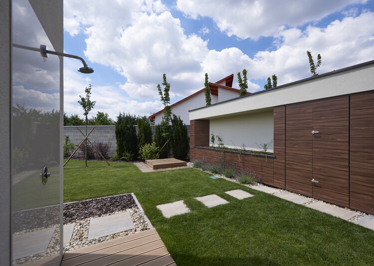 Moderner Garten mit Fundermax Max Compact Exterior Platten in Holzoptik, Rasen, Trittplatten und Außendusche.