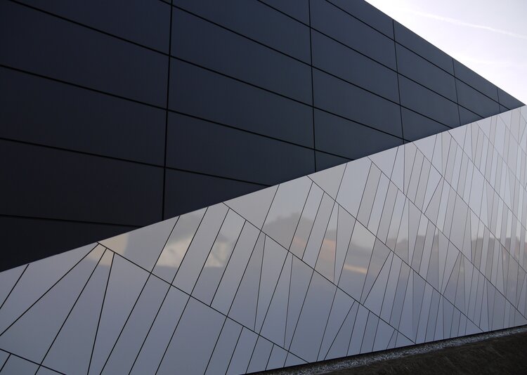 Moderne Fundermax Außenfassade des Eurospar St. Valentin mit glänzenden kieselgrauen Paneelen und geometrischen Linien.