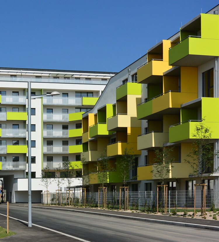 A passive housing complex on Kaisermühlenstraße featuring yellow and green Max Compact Exterior panels on the balconies.