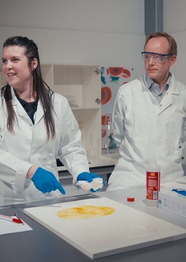 Lab Academy in Wiener Neudorf: Julia Kadnar und Hubertus Burger-Scheidlin demonstrieren, wie sich Laboroberflächen einfach reinigen lassen.  | © Felix Wagner