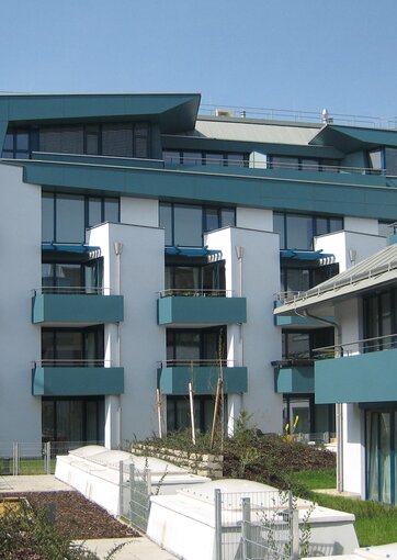 A modern apartment building with green balconies and facade elements.